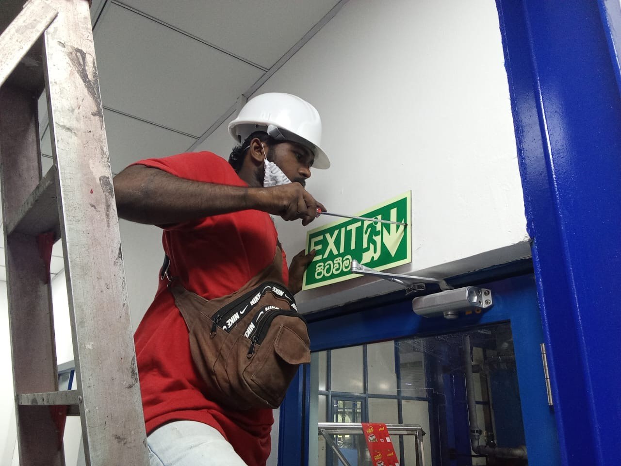 SAFE-X certified technician installing emergency exit light fixture