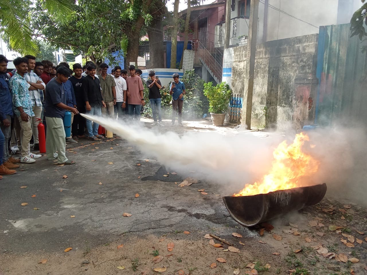 Trainee extinguishing industrial flammable liquid fire with fire extinguisher